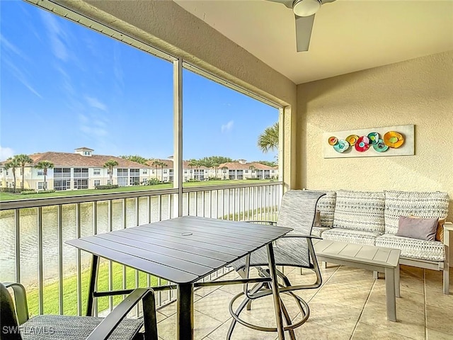 sunroom / solarium featuring a residential view, a water view, and a ceiling fan