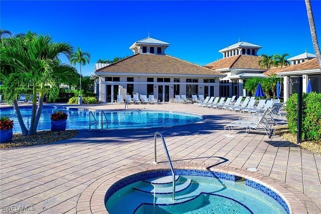 pool featuring a patio area, a community hot tub, and fence