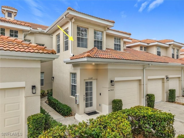 mediterranean / spanish-style house with a garage, driveway, and stucco siding