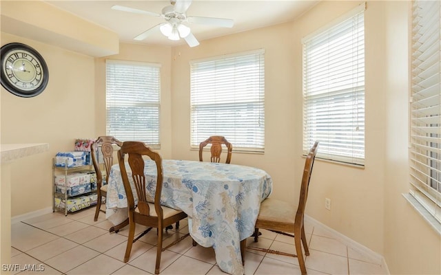 dining space with light tile patterned flooring, ceiling fan, and baseboards