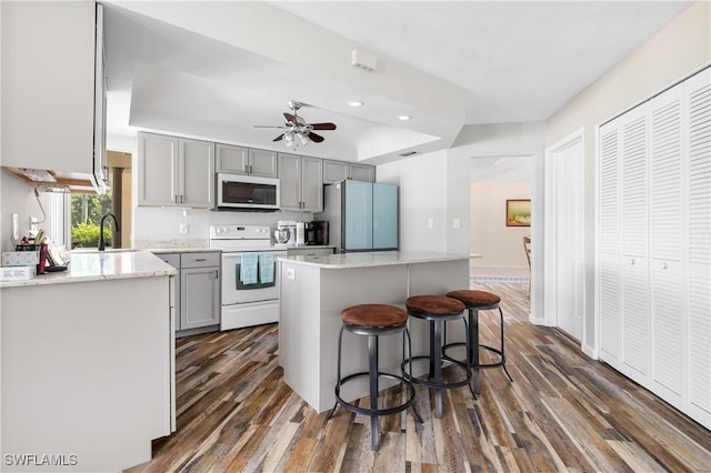 kitchen with electric range, stainless steel microwave, gray cabinets, and freestanding refrigerator