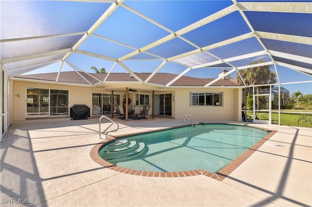 outdoor pool with glass enclosure, a patio, and ceiling fan