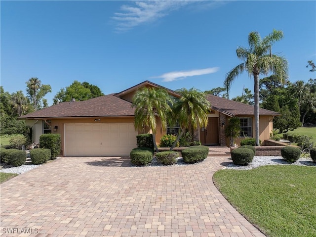 view of front facade with a front lawn, decorative driveway, and an attached garage