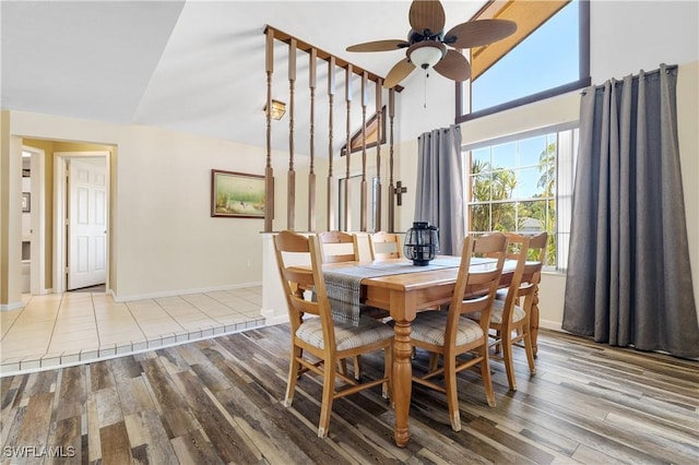 dining room featuring a ceiling fan, high vaulted ceiling, baseboards, and wood finished floors