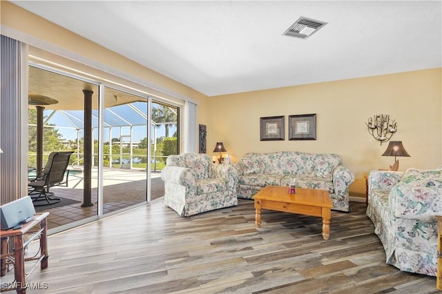 living room featuring visible vents, wood finished floors, and a sunroom