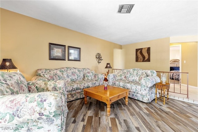 living room featuring visible vents, baseboards, and wood finished floors