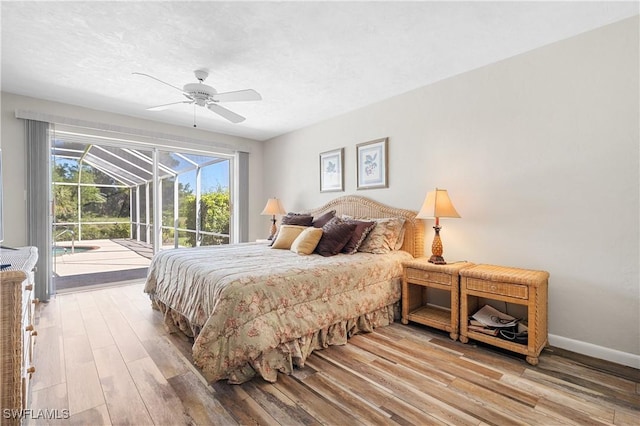 bedroom with baseboards, a sunroom, wood finished floors, access to outside, and a textured ceiling