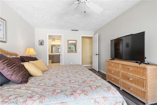 bedroom featuring visible vents, dark wood finished floors, ceiling fan, ensuite bathroom, and a textured ceiling