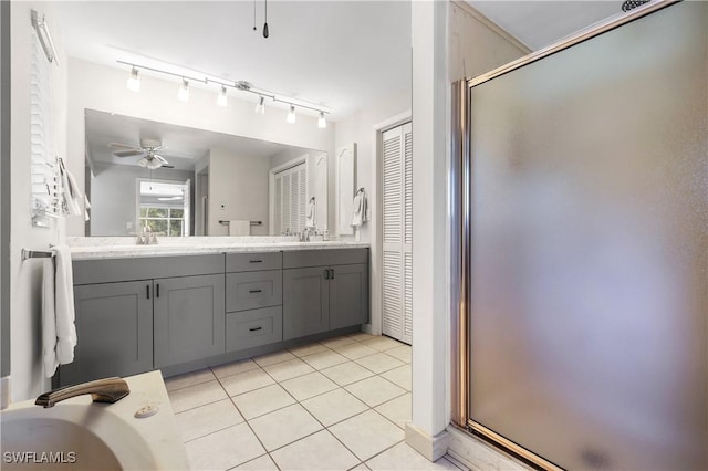 full bath with double vanity, a stall shower, ceiling fan, a sink, and tile patterned floors