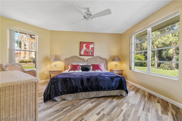 bedroom featuring a ceiling fan, baseboards, and light wood finished floors