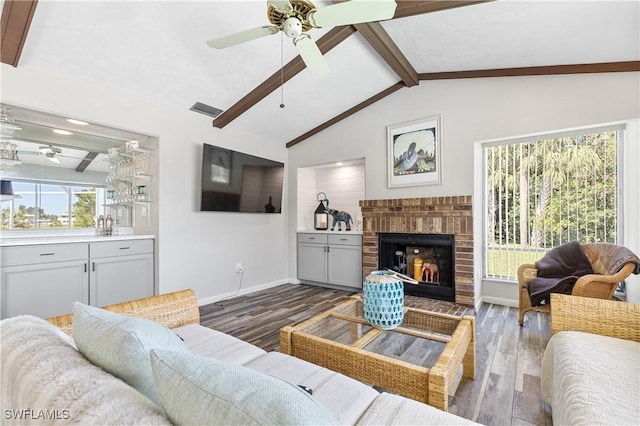 living area featuring vaulted ceiling with beams, a fireplace, visible vents, and wood finished floors