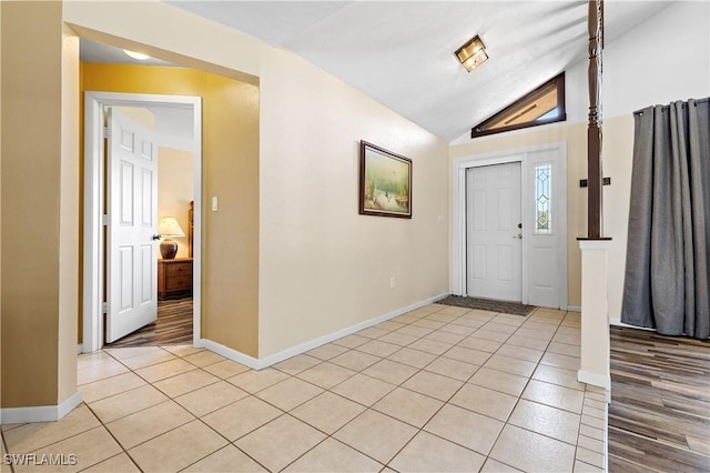 entryway featuring lofted ceiling, baseboards, and light tile patterned floors