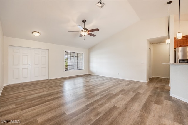 unfurnished living room with a ceiling fan, visible vents, vaulted ceiling, and wood finished floors