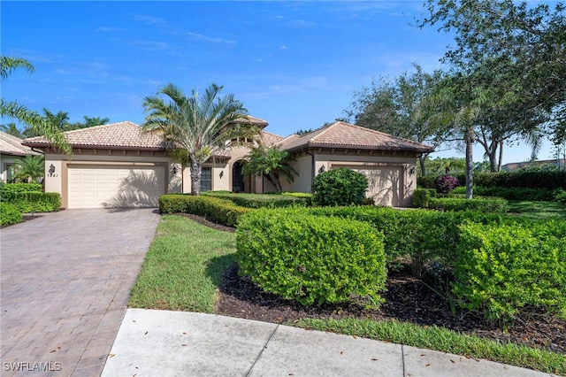 view of front of home featuring stucco siding, a tiled roof, decorative driveway, and a garage