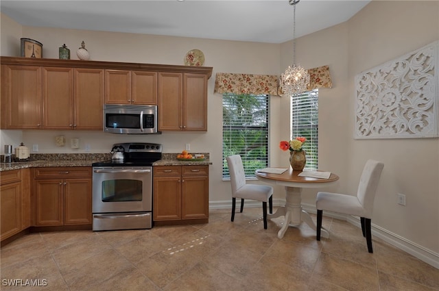 kitchen with dark stone countertops, brown cabinetry, baseboards, hanging light fixtures, and appliances with stainless steel finishes