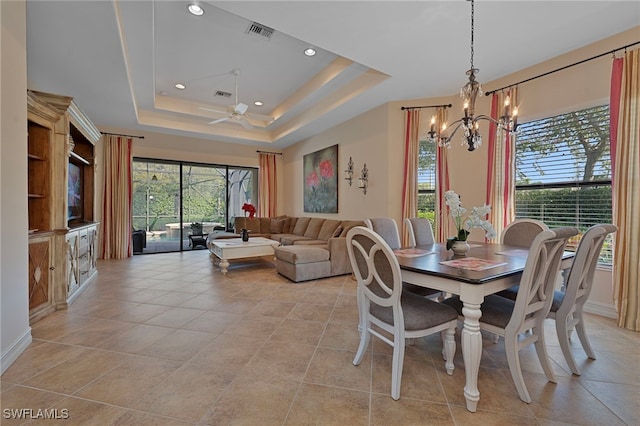 dining area with light tile patterned floors, visible vents, and a tray ceiling