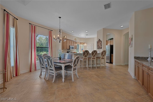 dining area featuring visible vents, arched walkways, an inviting chandelier, and a healthy amount of sunlight