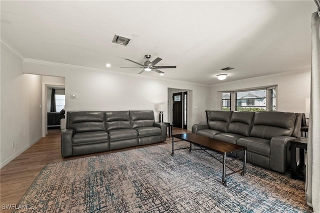 living area featuring ceiling fan, wood finished floors, visible vents, baseboards, and ornamental molding