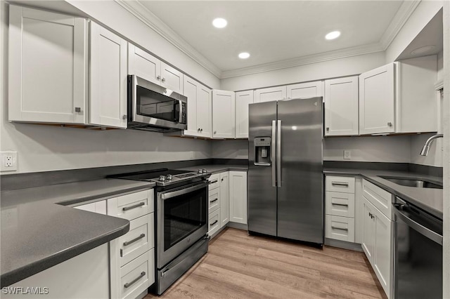 kitchen featuring appliances with stainless steel finishes, dark countertops, a sink, and crown molding