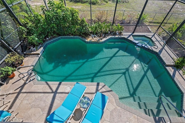 view of swimming pool with a pool with connected hot tub, glass enclosure, and a patio