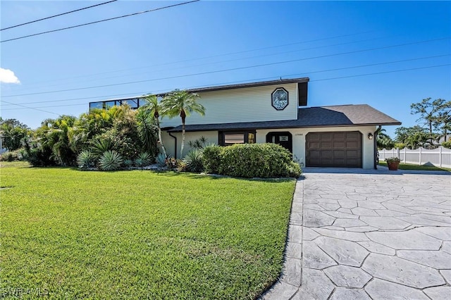 view of front facade with driveway, an attached garage, fence, and a front yard