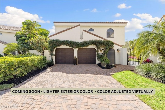 mediterranean / spanish home featuring a garage, a tile roof, a gate, decorative driveway, and stucco siding