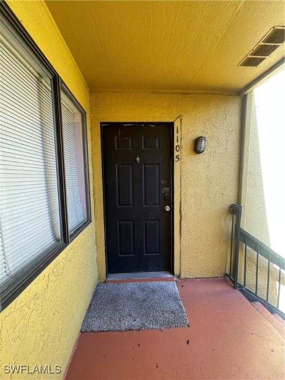 doorway to property featuring visible vents and stucco siding