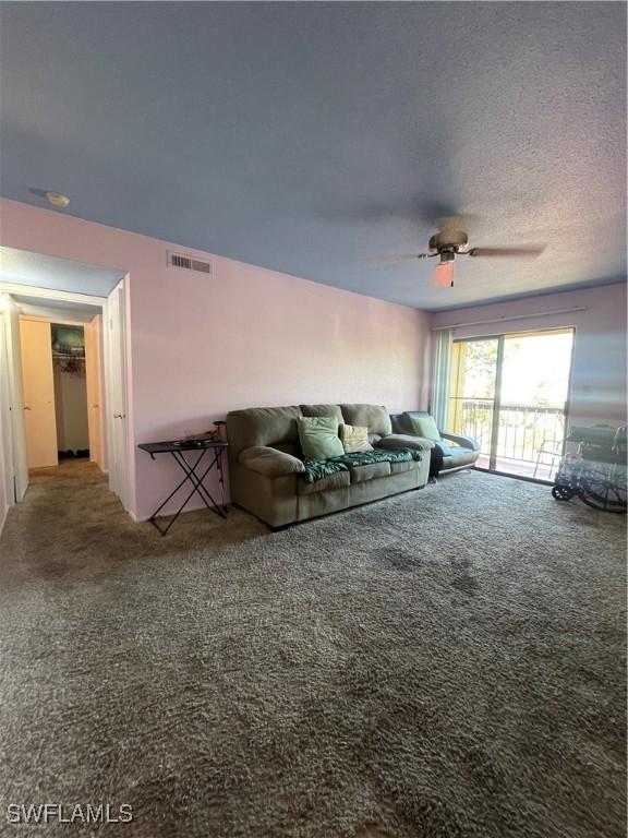 living room with a textured ceiling, ceiling fan, carpet, and visible vents