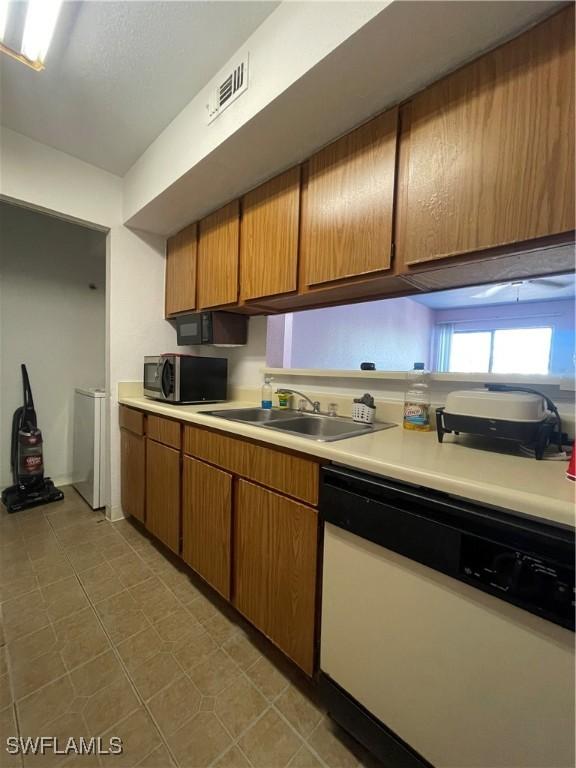 kitchen with a sink, stainless steel microwave, light countertops, and dishwasher