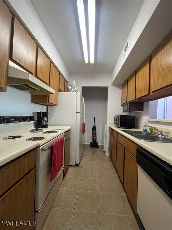 kitchen with white appliances, visible vents, light countertops, under cabinet range hood, and a sink