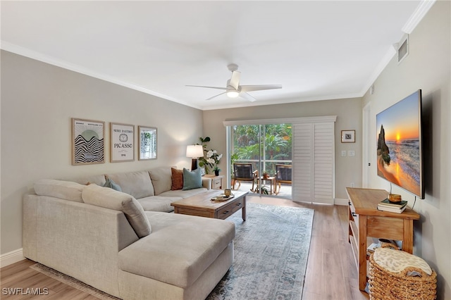 living area featuring visible vents, light wood-style flooring, a ceiling fan, crown molding, and baseboards