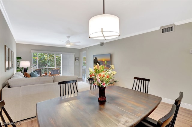 dining room featuring light wood finished floors, visible vents, and ornamental molding