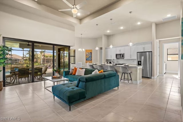 living room featuring a towering ceiling, light tile patterned floors, recessed lighting, and ceiling fan with notable chandelier