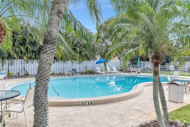 community pool with a patio and fence