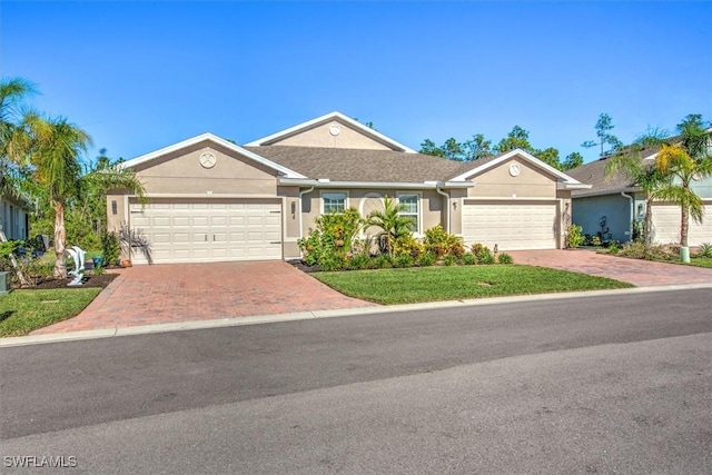 ranch-style home featuring decorative driveway, an attached garage, and stucco siding