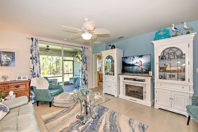 living area featuring light tile patterned flooring, ceiling fan, and visible vents