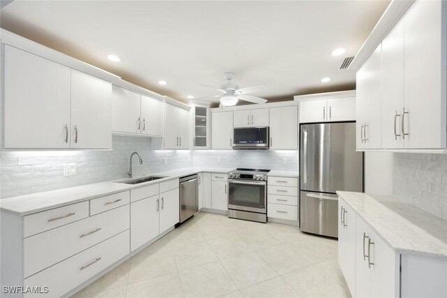 kitchen featuring ceiling fan, a sink, white cabinets, appliances with stainless steel finishes, and tasteful backsplash