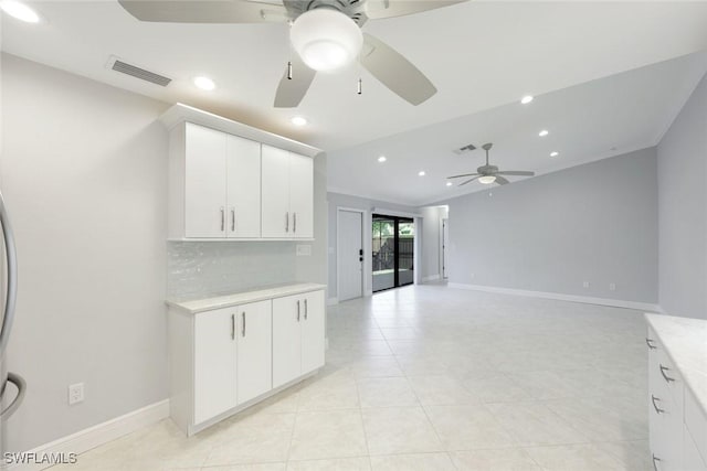 kitchen featuring baseboards, light countertops, visible vents, and decorative backsplash