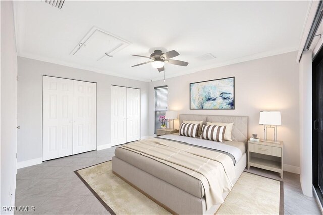 bedroom featuring visible vents, ornamental molding, ceiling fan, and two closets