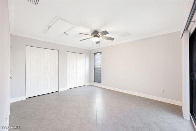 unfurnished bedroom with ornamental molding, two closets, and baseboards