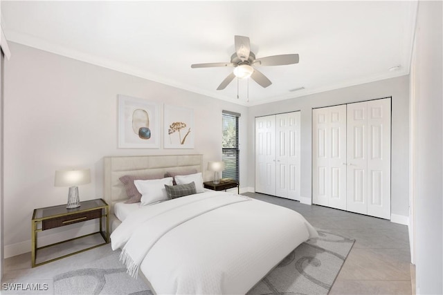 bedroom with baseboards, visible vents, a ceiling fan, ornamental molding, and multiple closets