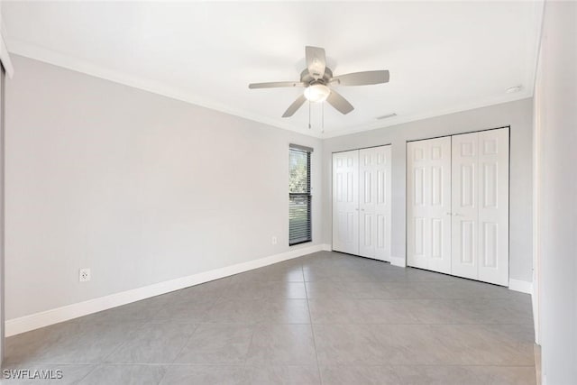 unfurnished bedroom featuring baseboards, two closets, and ornamental molding