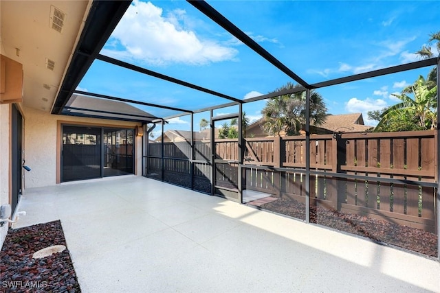 view of patio with glass enclosure, a fenced backyard, and visible vents