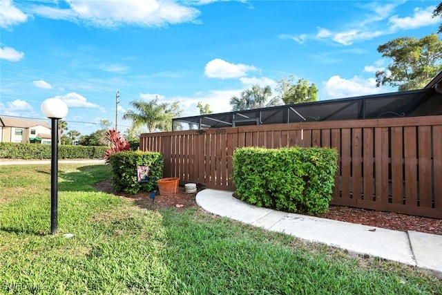 view of yard featuring glass enclosure and fence