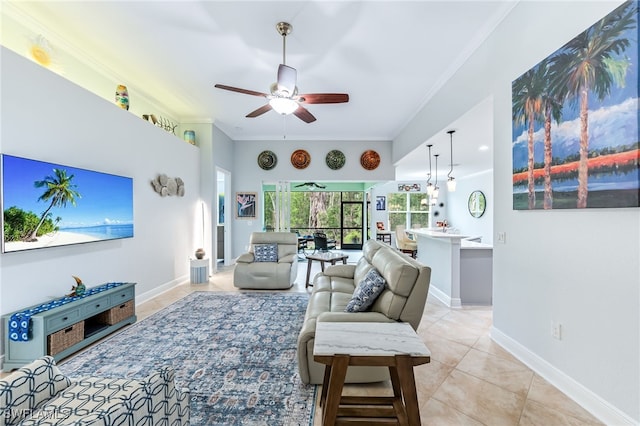 living area with ornamental molding, ceiling fan, baseboards, and light tile patterned floors