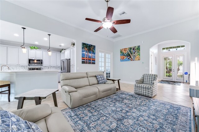 living area featuring light tile patterned floors, arched walkways, visible vents, ornamental molding, and french doors