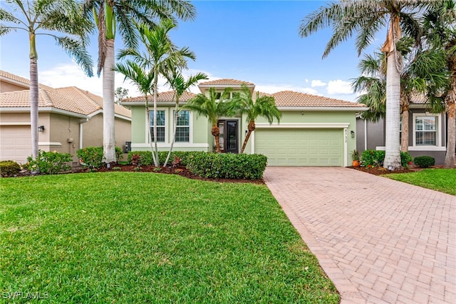 mediterranean / spanish-style house with decorative driveway, a tile roof, stucco siding, an attached garage, and a front yard