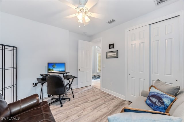 office space with light wood-type flooring, visible vents, arched walkways, and baseboards