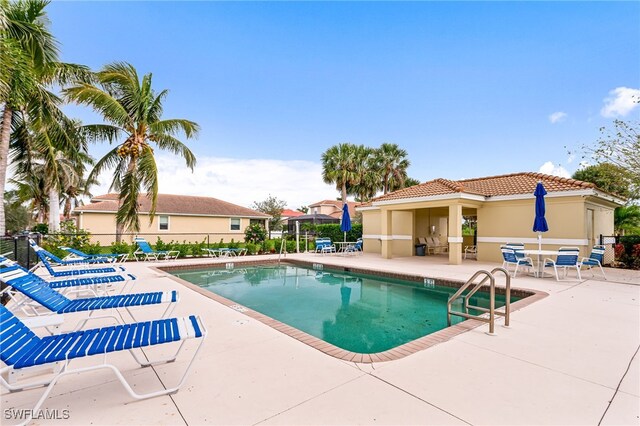 community pool with a patio area and fence