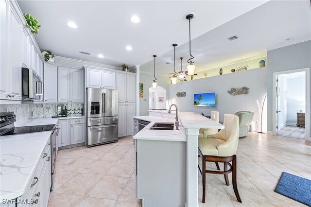 kitchen featuring light tile patterned floors, stainless steel appliances, backsplash, ornamental molding, and a sink